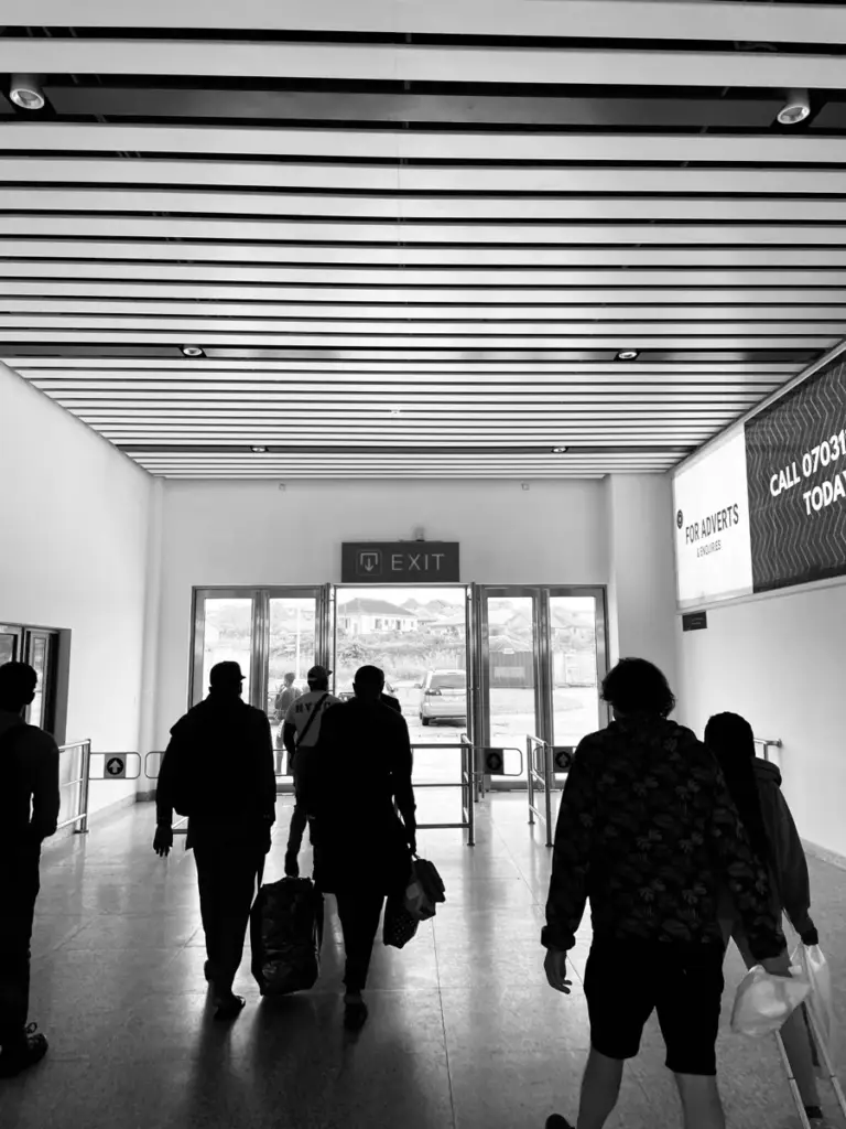 Black and white shot of travellers walking towards a station exit