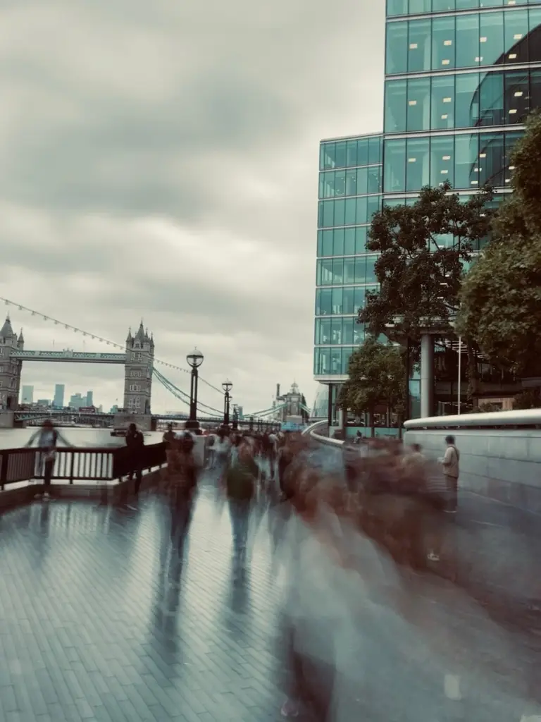 Long exposure of crowds blurring along the Thames path, with Tower Bridge behind